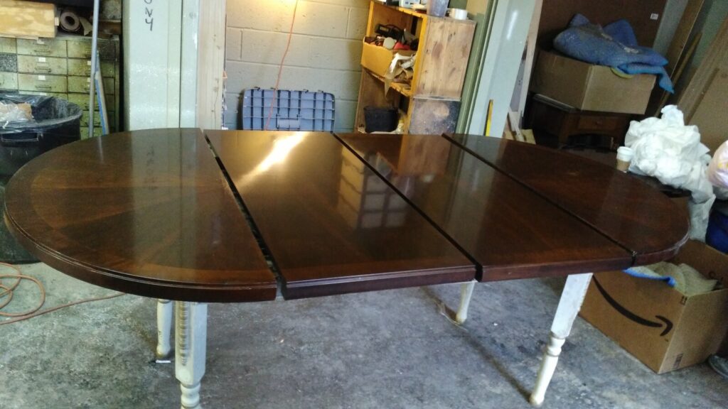 Refinished wood dining table completed in the workshop, showing the final restored surface.