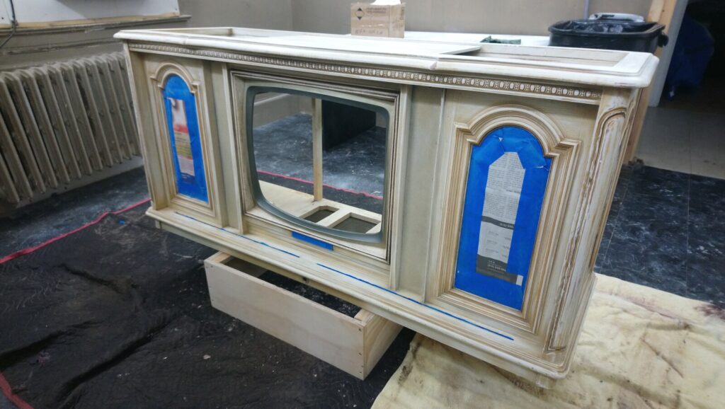 Antique cabinet in the spray room before refinishing, shown with its original worn finish.