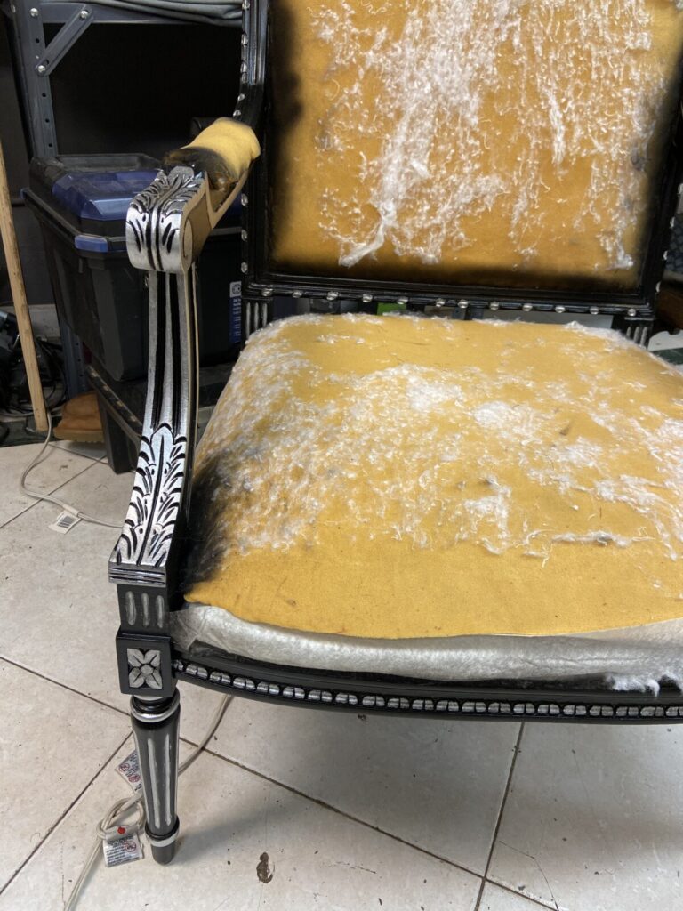 Antique black chair with the arm fully finished in silver leaf, shown after restoration.