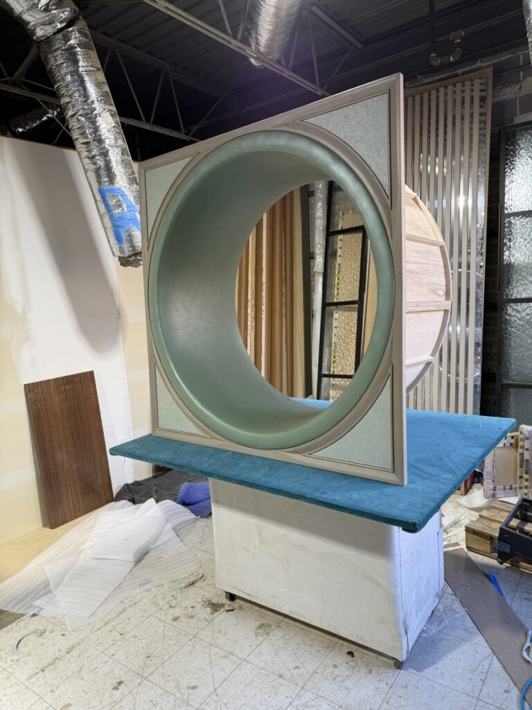 Mid-installation view showing integrated shelving and the application of brown velvet to the arched wall frames.