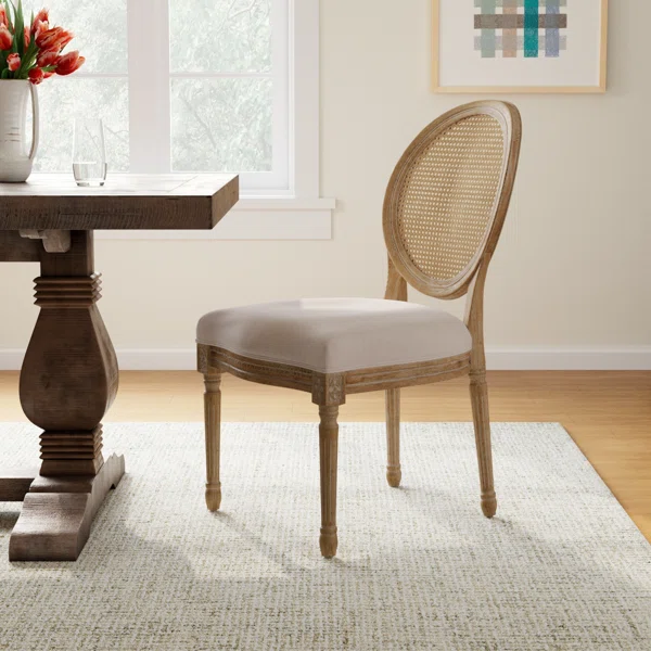 Wooden dining chair with a light upholstered seat and a cane backrest beside a dining table.