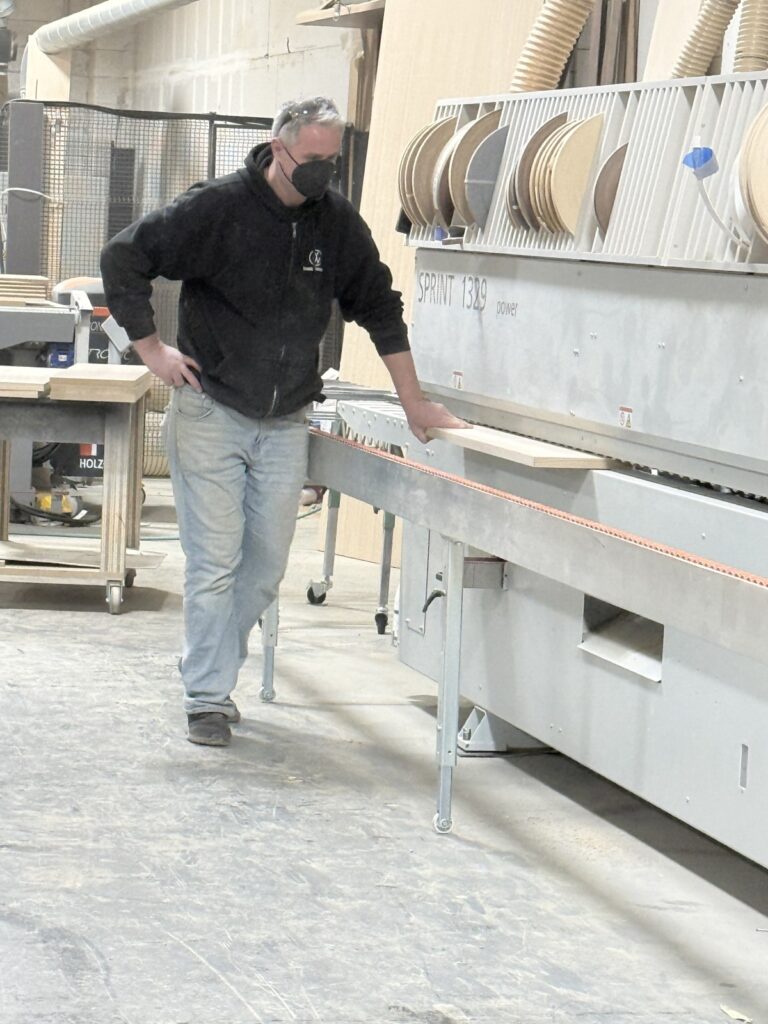 A craftsman operating an architectural millwork production machine at the first class mastercraft workshop in west nyack, building custom wood frames for banquettes and furniture.